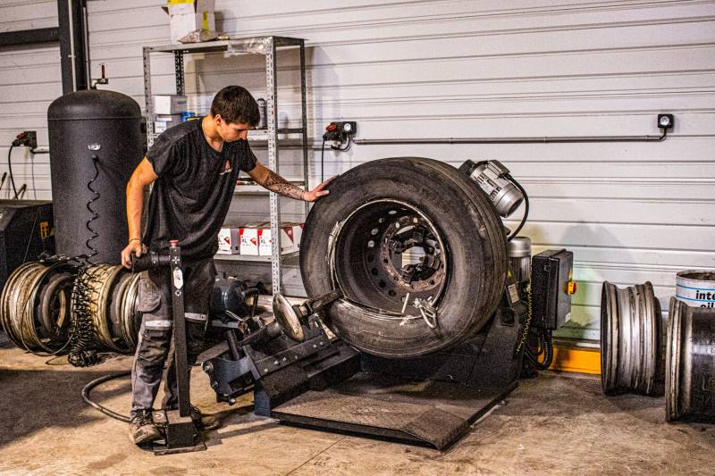 Mécanicien mettant en place le pneu sur la jente - Atelier - Mazères